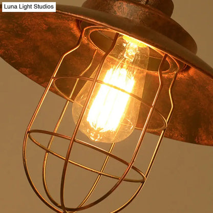 Rustic copper industrial pendant light with wire cage and glowing filament bulb in weathered copper pipe design