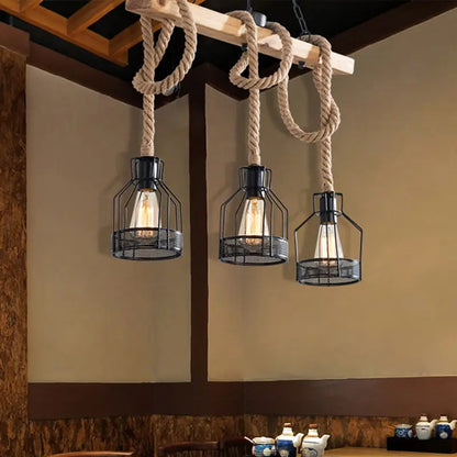 Three black metal cage pendant lights with exposed bulbs suspended by beige rope from wooden beam for restaurants