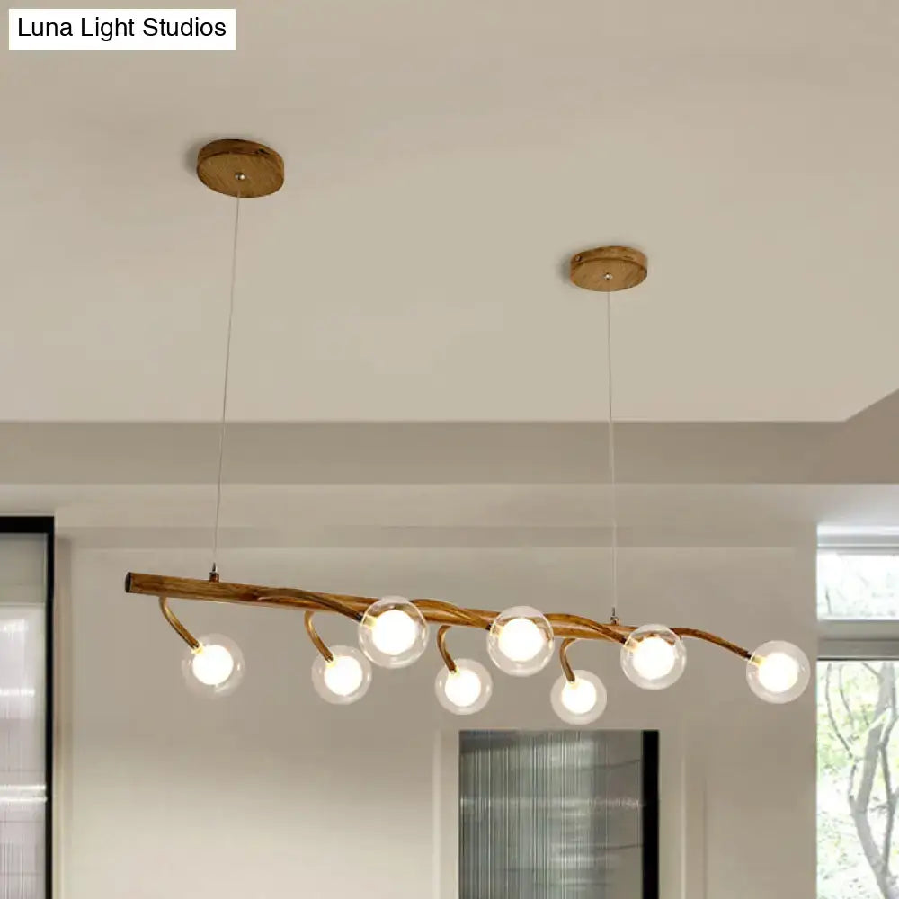 Modern pendant light with brown wooden branch design and brass fittings featuring modo clear glass shade for dining hall