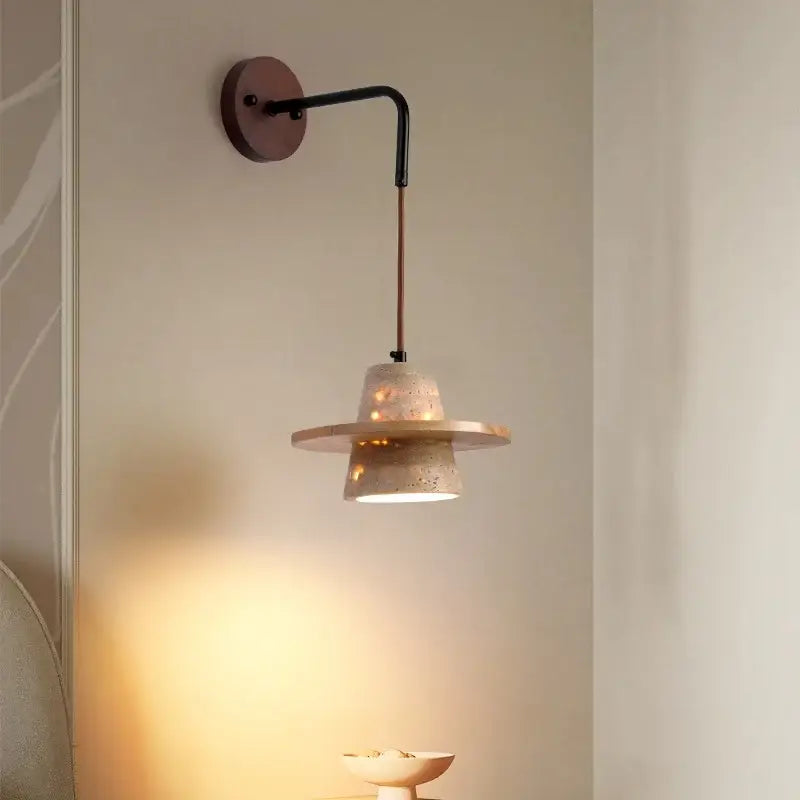 A modern wall lamp with a textured beige concrete shade, black metal arm, and pull chain switch for bedroom use