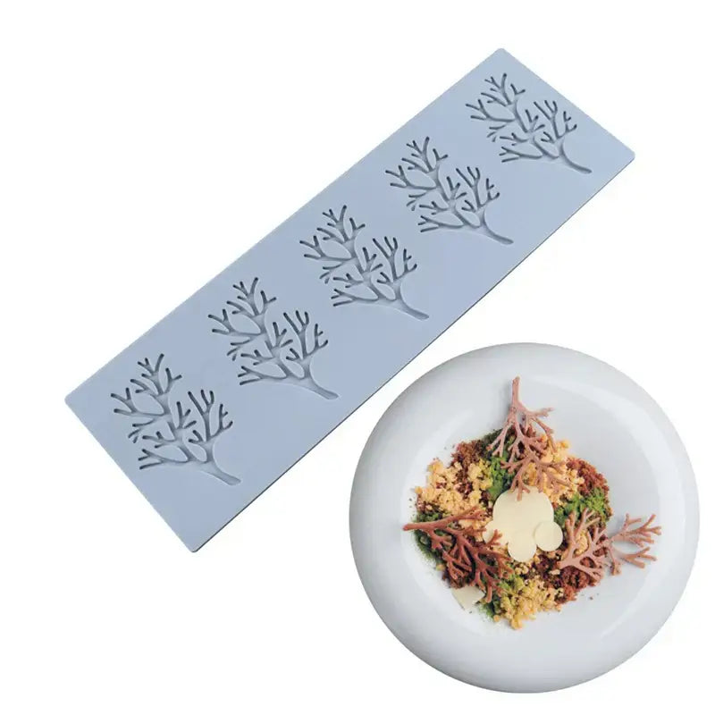 Light blue silicone mold shaped like coral branch leaf with matching edible decorbites coral branch garnish on white plate