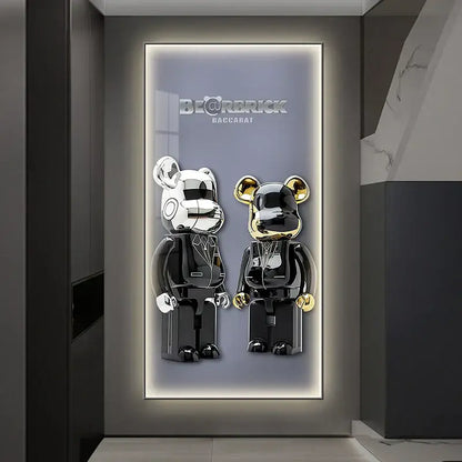 Two glossy silver and gold bearbrick figures in black suits displayed against an iron man led wall lamp for bedroom decor