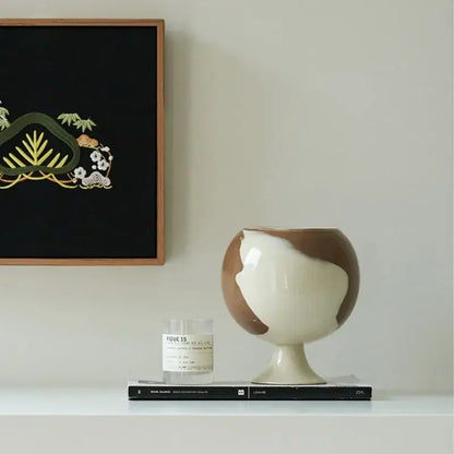 A glossy two-toned ceramic irregular grain spherical vase in cream and brown decorbites irregular grain decor
