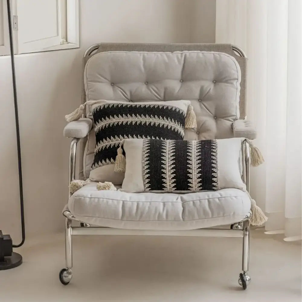 A sleek armchair with tufted beige upholstery and chrome legs complements decorbites jacquard crochet pillow covers