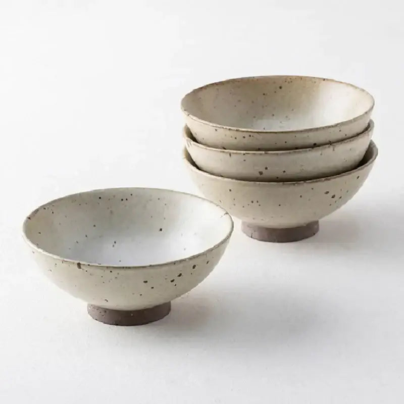 Set of four beige and brown handmade ceramic rice bowls with speckled finish and footed bases for dining room use