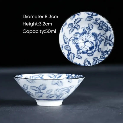 A delicate white ceramic kung fu tea cup with intricate blue floral patterns and matching lid in traditional porcelain style