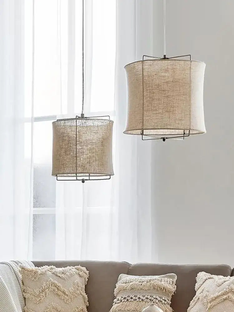 Two beige decorbites linen fabric chandelier pendant lamps with black metal frames hang from the ceiling in a bedroom