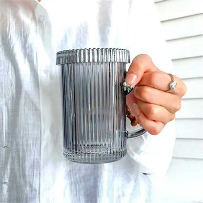 A translucent gray ribbed glass coffee cup from decorbites glass coffee cup set held by a hand with rings