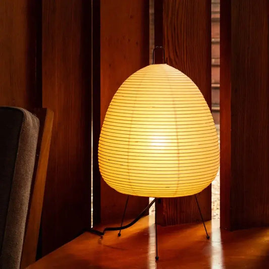 Warmly glowing japanese style rice paper desk lamp with egg-shaped shade and minimalist black metal stand for decorbites bedroom lighting