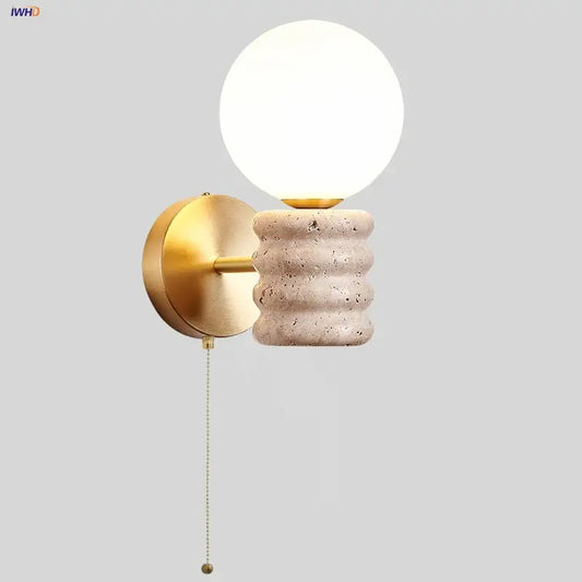 Gold-toned led wall lamp with textured off-white Japanese travertine base and frosted glass globe shade for bedroom use