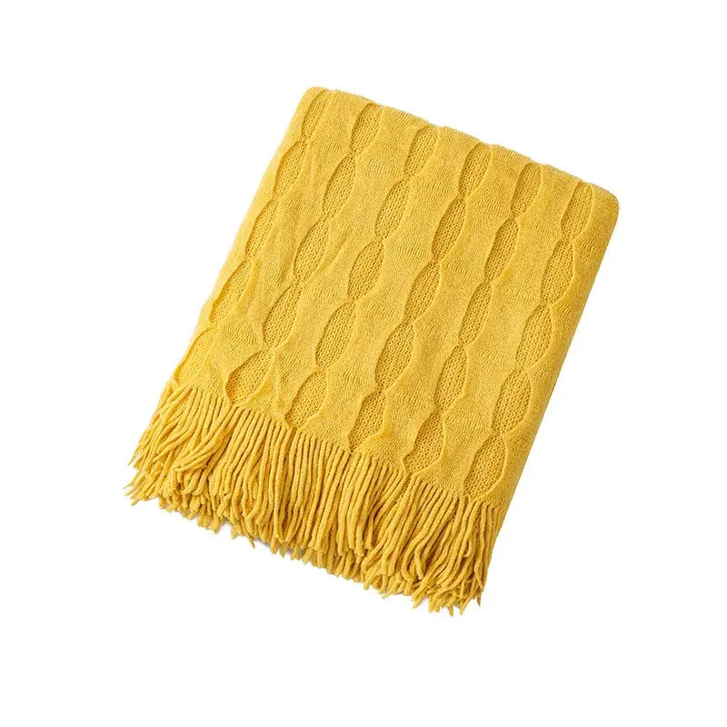 A cozy mustard-yellow decorbites knitted geometric throw blanket with cable-knit texture and tassels for bedroom decor