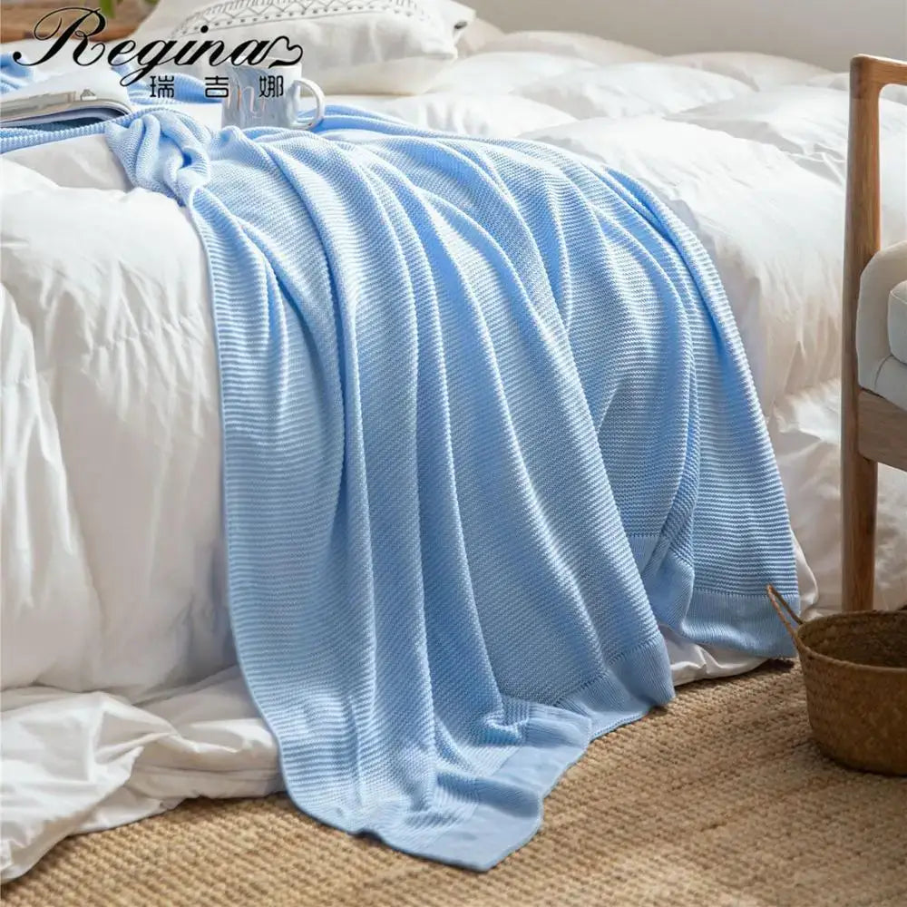 A soft light blue knitted bamboo cooling throw blanket with ribbed texture and loose weave for bedroom bedding