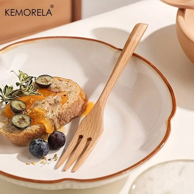 A white ceramic plate with brown rim and scalloped edge featuring kemorela logo displayed with wooden fork spoon set