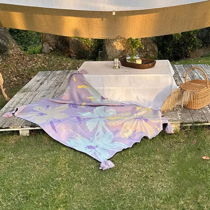 Lavender floral cozy knit blanket with tassels draped on a wooden deck decorbites cozy knit living room throw