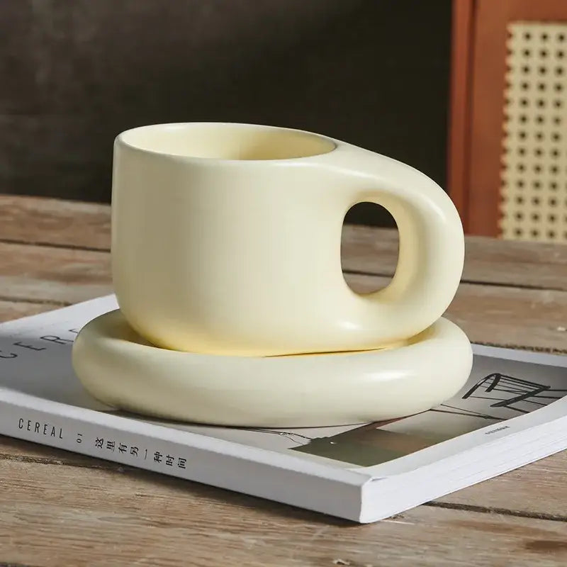 Cream-colored ink splash ceramic mug with smooth rounded handle and matching oval plate from decorbites ink splash set
