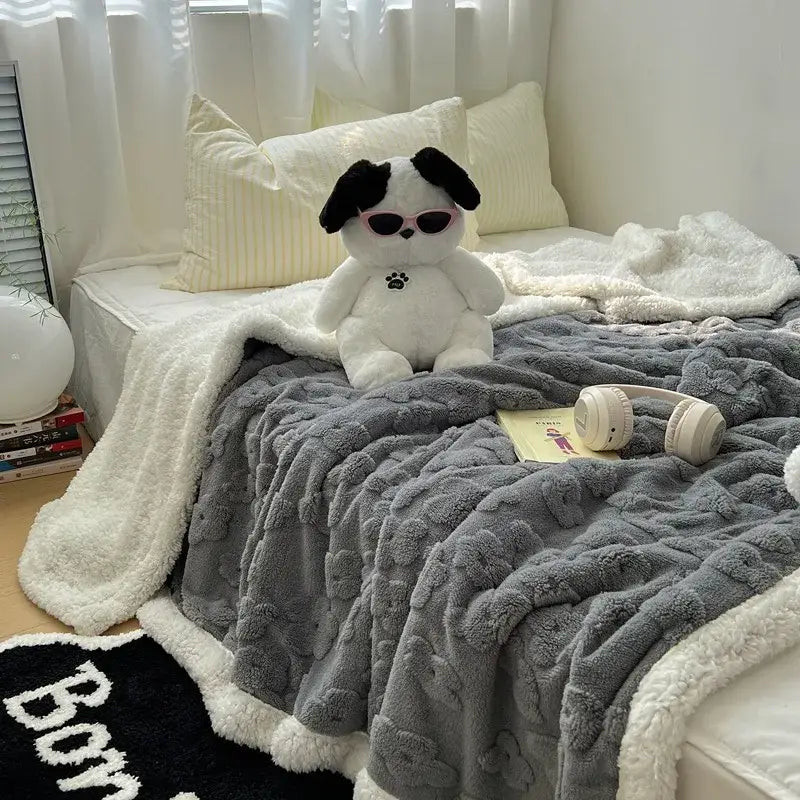 A plush white and black dog toy with pink sunglasses sits on a lavender and white cozy lamb wool flower throw blanket