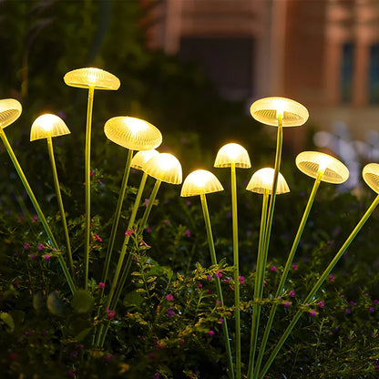 Glowing yellow LED solar jellyfish mushroom lamp with slender green stems for outdoor garden and lawn decoration lighting