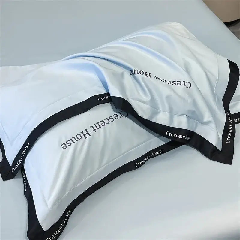 White satin pillowcase with black trim and crescent house branding as part of decorbites ice silk duvet cover bed set