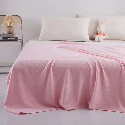 Soft pink textured bedspread draped over a bed featuring bamboo fiber summer quilt with diamond grid design