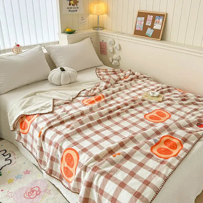 A cream and rust plaid cozy milk velvet blanket with cartoon orange slices featuring soft fleece texture for decorbites cozy milk