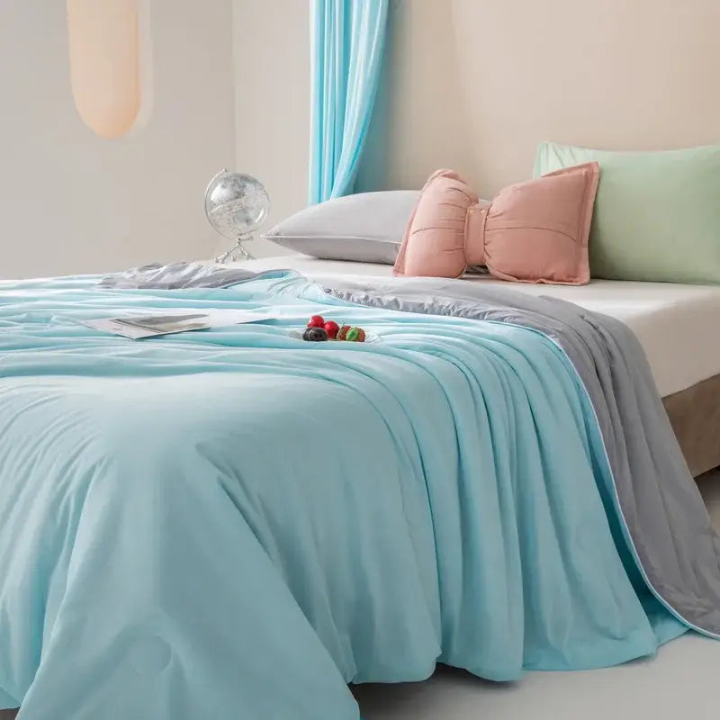Light blue quilted cool fiber summer blanket with a soft plush texture and subtle gray trim by decorbites cool fiber