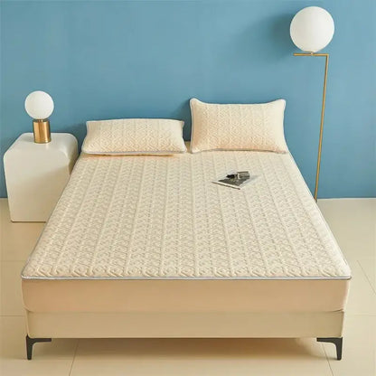 Cream-colored quilted mattress protector with subtle geometric pattern and stitched edges for fitted sheet set use
