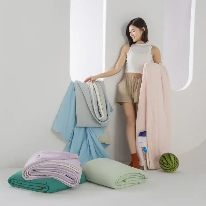 A woman stands beside neatly folded light blue and white decorbites cooling fabric summer blankets for bedroom comfort