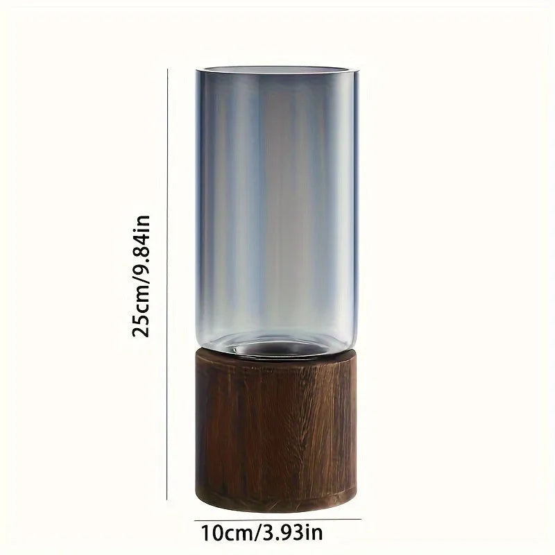 Tall cylindrical glass vase with gradient gray to clear finish on dark brown wooden base for living room decoration