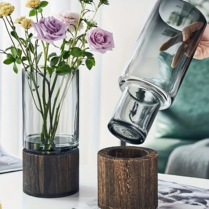 Tall clear glass vase with dark wood base holding purple and yellow roses for living room table decoration