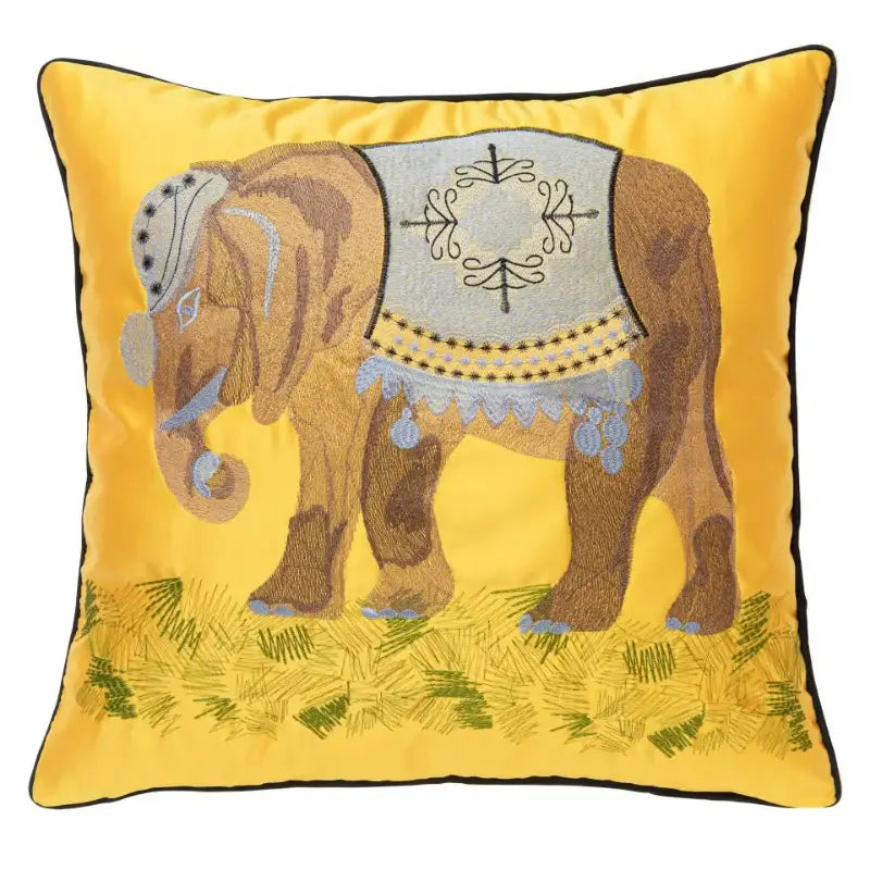 Vibrant yellow satin cushion cover with decorbites elephant embroidery featuring gray saddle and blue tassels on grass