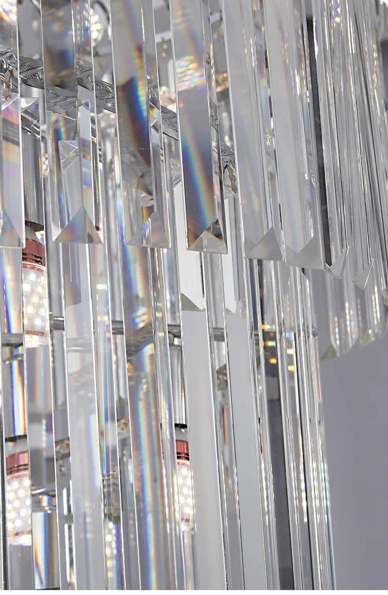 A modern long crystal staircase gold chandelier with clear crystal prisms refracting light for hotel hall decor