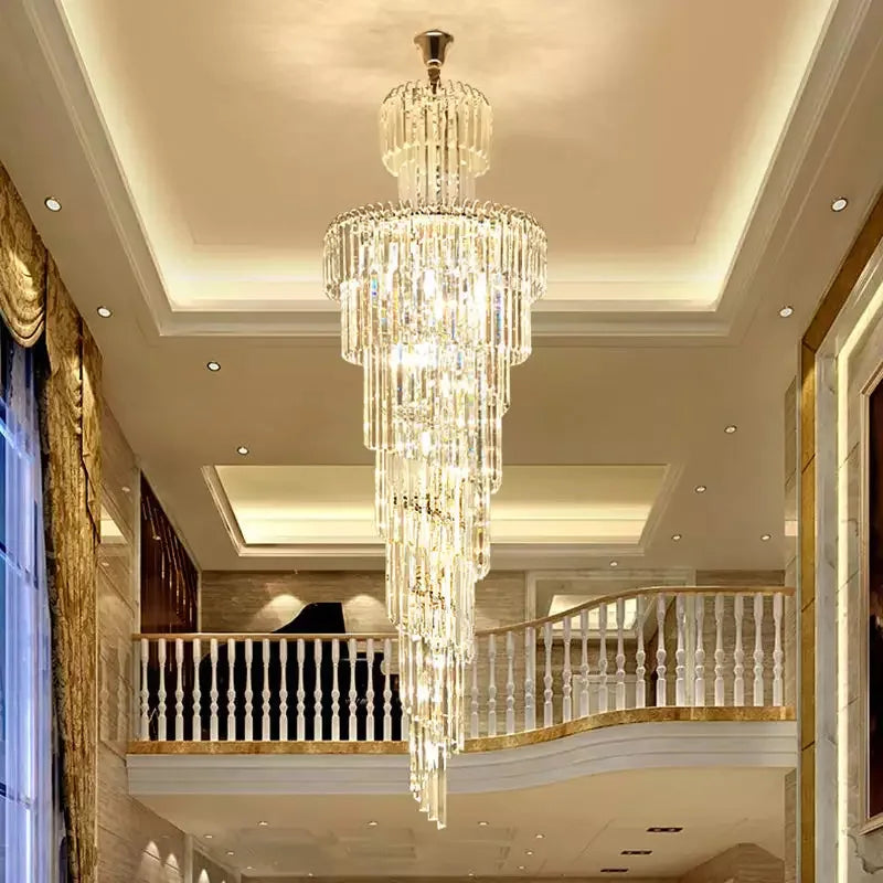 A multi-tiered crystal staircase gold chandelier with clear glass prisms and polished brass for hotel hall decor