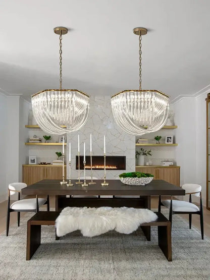 Two elegant crystal-encrusted chandeliers with gold-toned frames hang above a decorbites black stainless steel dining table light