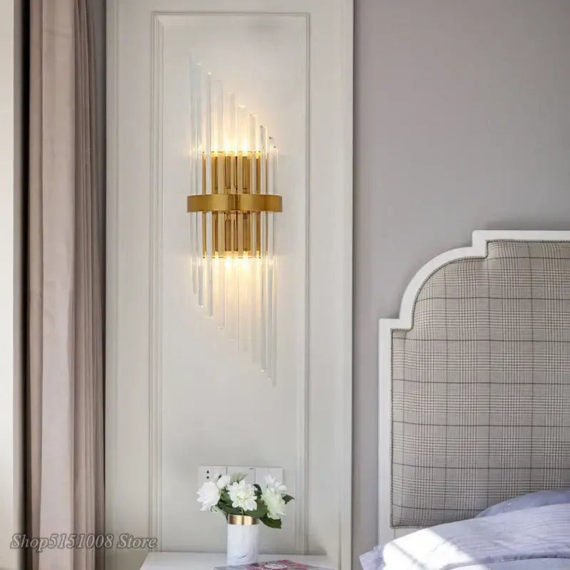 Gold-toned decorbites crystal golden wall lamp with vertical crystal rods and circular base for living room decor