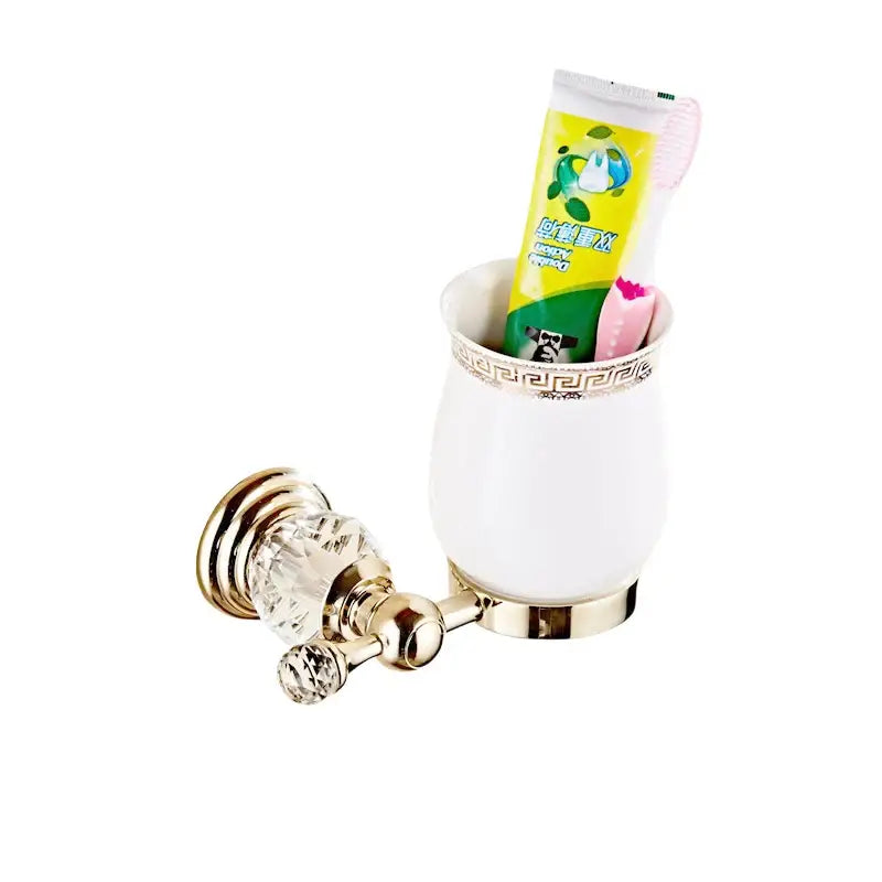 White ceramic toothbrush holder with gold-toned metal accents and greek key pattern in luxury bath hardware set
