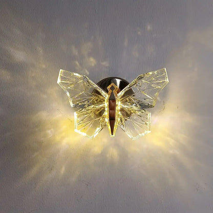 Luxury gold butterfly wall lamp featuring a clear crystal geometric butterfly with a metallic mounting base for bedroom lighting