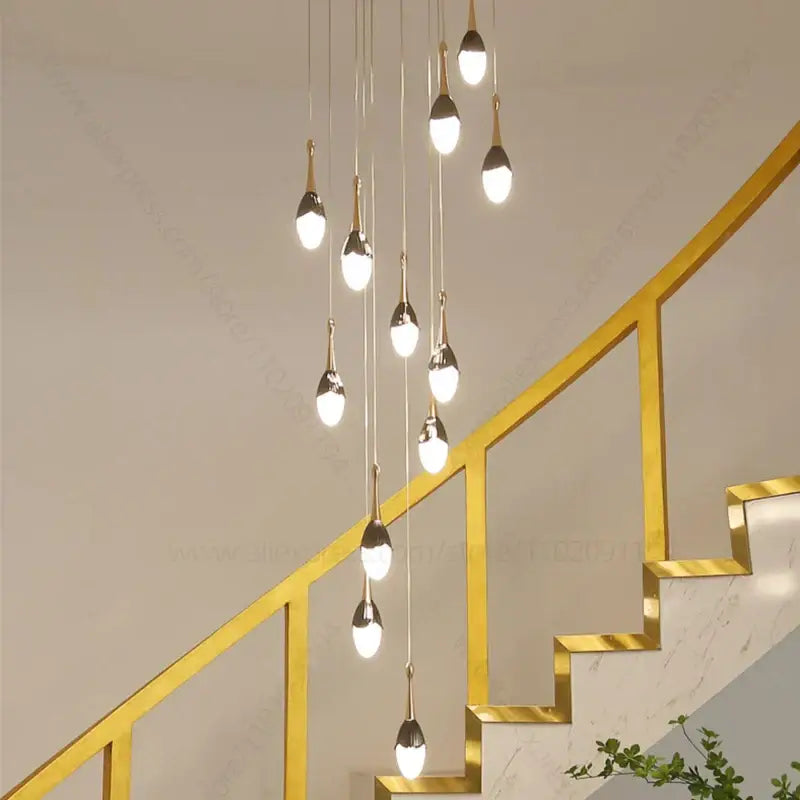 Modern gold-toned decorbites gold led staircase chandelier with teardrop glass shades above staircase for living room decor