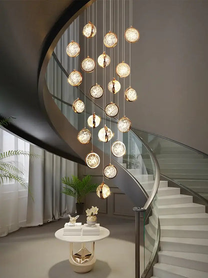 A luxury golden decorbites crystal ball led rotating stair chandelier with multiple glowing spherical glass orbs suspended by thin chains