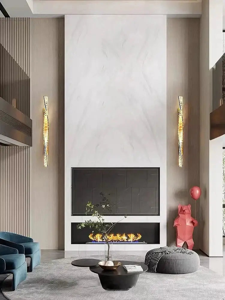 A sleek black fireplace with glowing flames set in white marble wall complements luxury golden twisted crystal led wall sconce decorbites crystal led wall
