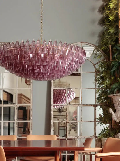 A glamorous decorbites gray glass chandelier with cascading pink teardrop crystals hangs from a gold chain