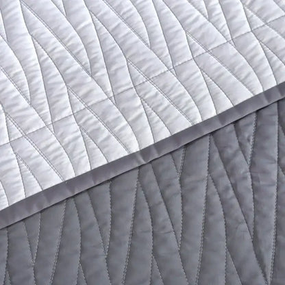 A soft quilted throw blanket with a modern gray geometric pattern from a luxury egyptian cotton quilt set