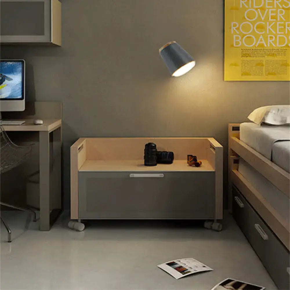 Gray and light wood storage bench with wheels placed below a macaron pink and gold fabric wall lamp fixture in bedroom