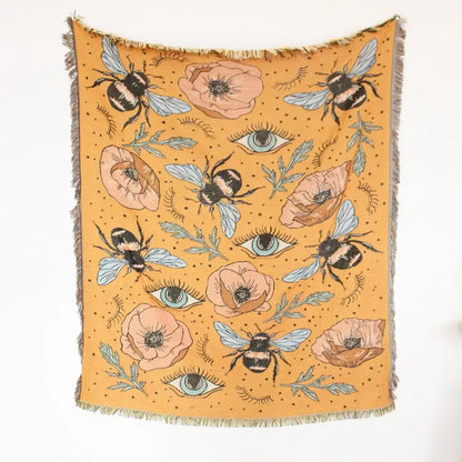 Mustard-yellow woven geo tassel picnic mat and sofa cover with bee poppy and teal eye pattern on dotted background