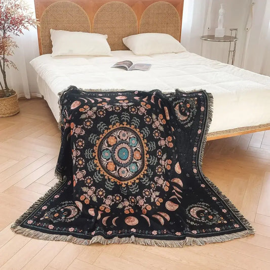 Black throw blanket with intricate mandala design and fringed edges used as geo tassel picnic mat and sofa cover