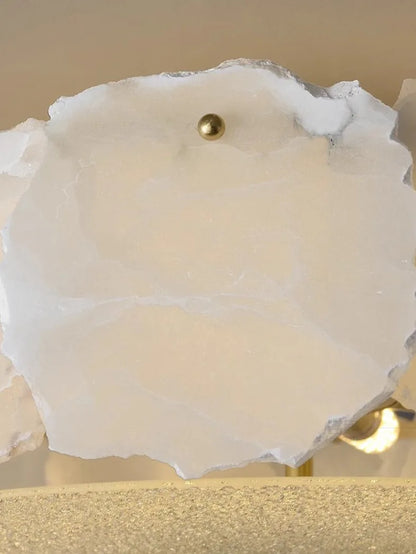 A white translucent geode slice with a golden sphere in the center in a marble led chandelier round pendant light