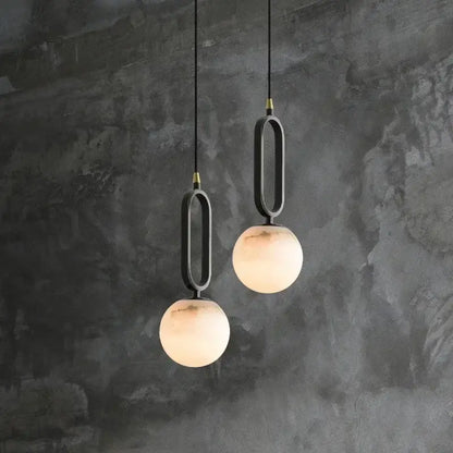 Two matte black pendant lights with frosted glass spheres and polished copper accents for dining room lighting