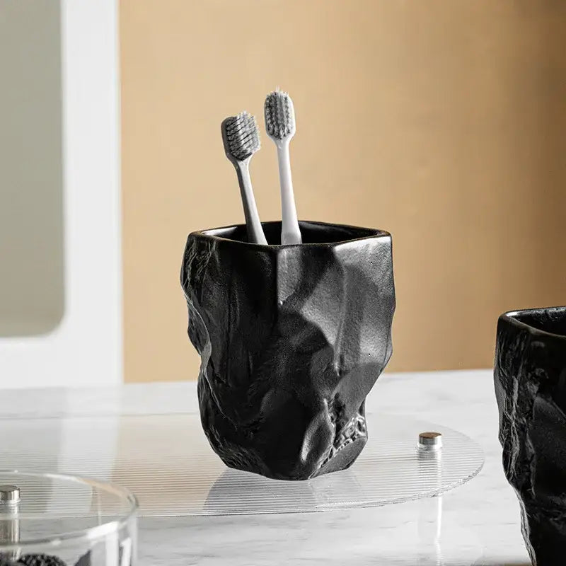 Matte black irregular shaped mouthwash cup silicone mold with a rugged cracked stone texture for bathroom use