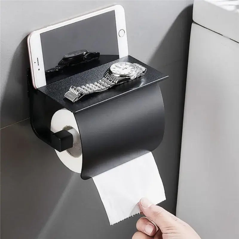 Matte black and silver wall-mounted toilet paper holder with shelf for phone and watch storage in bathroom