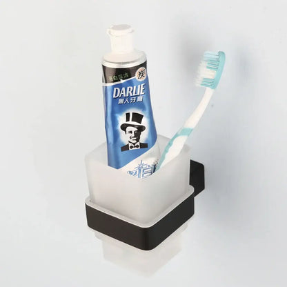 Matte black stainless steel bathroom hardware set featuring a sleek two-toned toothbrush and toothpaste holder with frosted glass