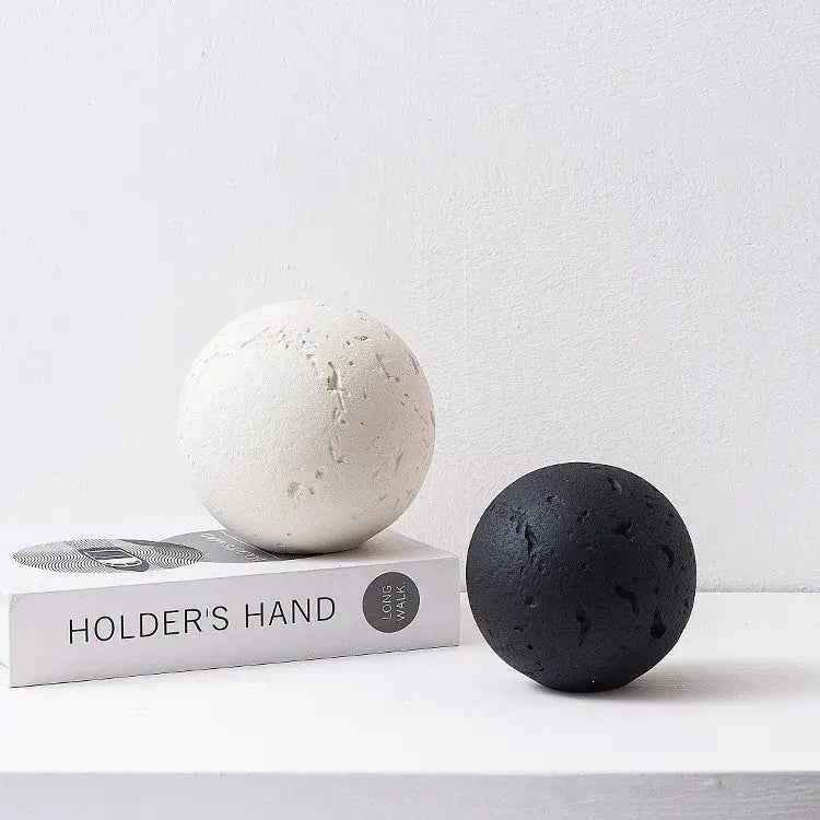 Matte finished spherical home decoration accessory in off-white and black with textured volcanic rock surface